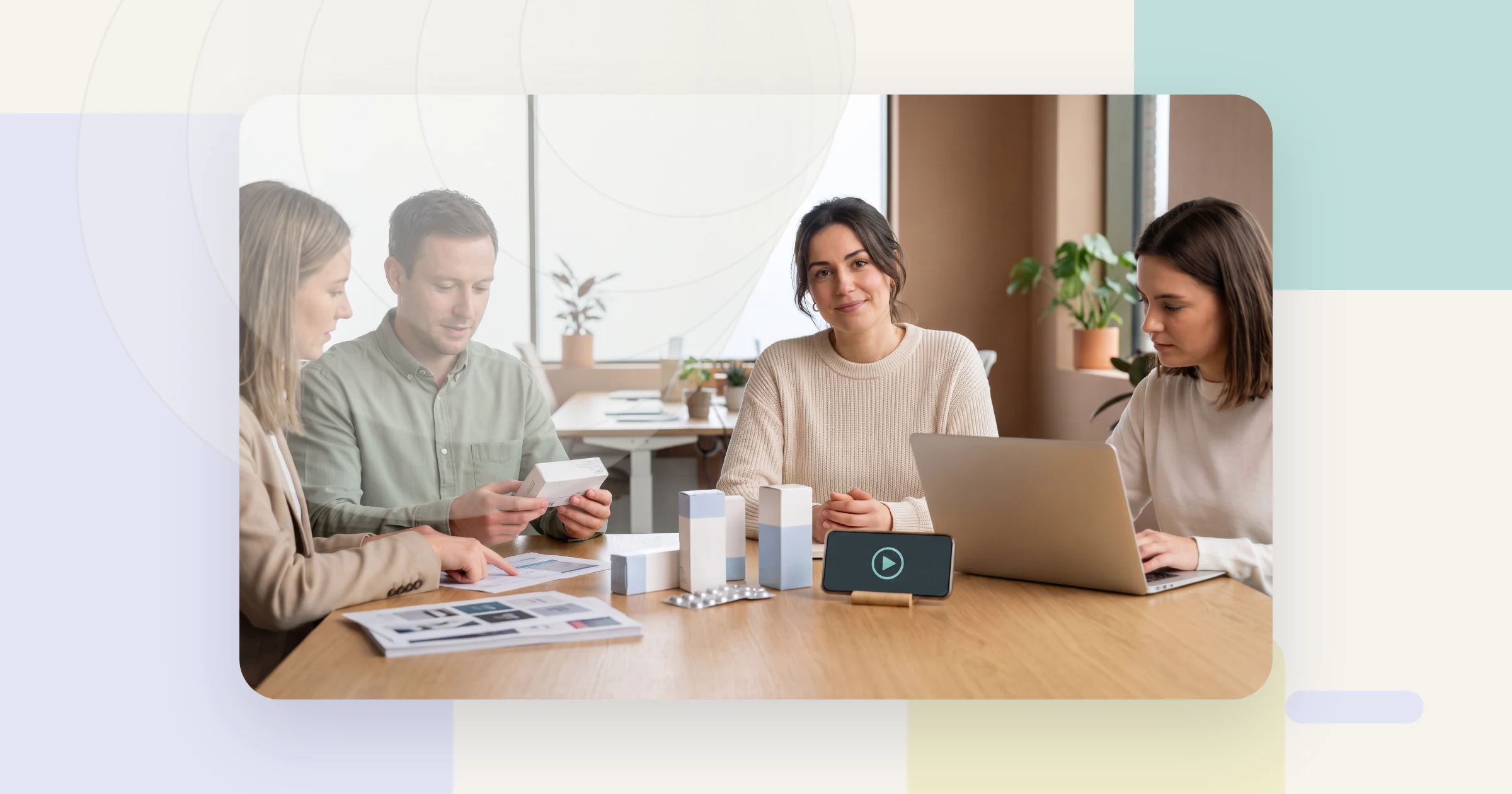 Pharma video pilot rollout: a cross-functional project team reviews medicine packaging mock-ups while a phone plays the QR-linked patient video